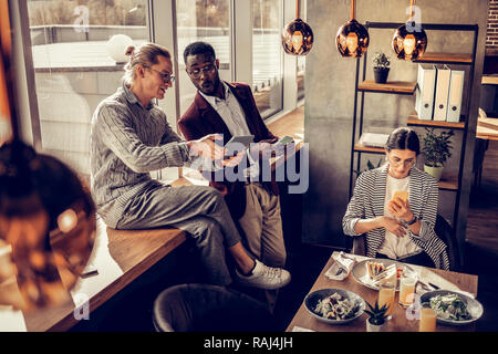 Emotionale internationale männliche Person an Tablet starrte Stockfoto