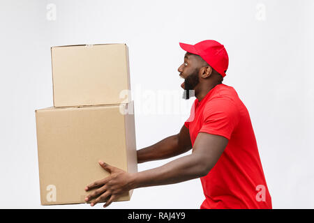 Portrait von Lieferung afrikanische amerikanische Mann im roten T-Shirt. Er Heben von schweren Gewicht Boxen gegen eine auf weißem Hintergrund. Stockfoto
