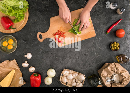 7/8-Ansicht von Frau Zerkleinern von Gemüse auf Schneidebrett mit pizza Zutaten auf grauem Hintergrund Stockfoto