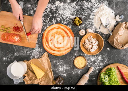 Teilweise mit Blick auf die Frau zu hacken, Chilischote, beim Kochen Pizza auf grauem Hintergrund mit Mehl Stockfoto