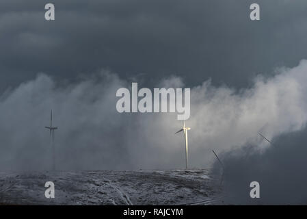 Winterlandschaft mit Windkraftanlagen und der Wolken auf einem schneebedeckten Berg Feld Stockfoto