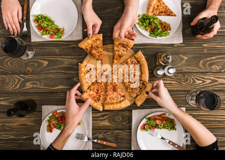 Anzeigen von Freunden teilen Pizza beim Abendessen mit Salaten an den hölzernen Tisch 7/8 Stockfoto
