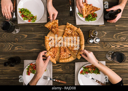 Teilweise mit Blick auf die Freunde teilen Pizza beim Abendessen mit Salaten an den hölzernen Tisch Stockfoto