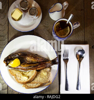 Craster kipper serviert mit Toast zum Frühstück in Northumberland, England. Die northumbrian Delikatesse ist mit Earl Grey Tee serviert. Stockfoto