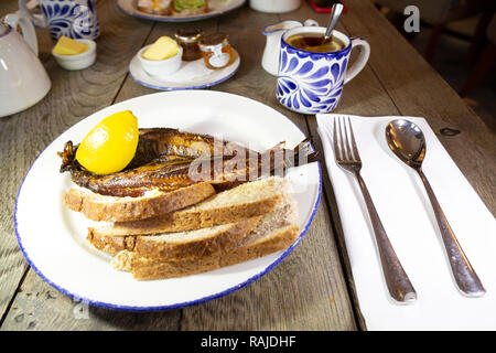 Craster kipper serviert mit Toast zum Frühstück in Northumberland, England. Die northumbrian Delikatesse ist mit Earl Grey Tee serviert. Stockfoto