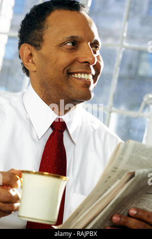 Afrikanische amerikanische Geschäftsmann genießt seinen morgendlichen Kaffee und Zeitung, USA Stockfoto