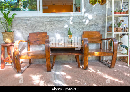 Zwei Vintage Stühle aus Holz auf Zement Veranda und poliert Zement Wand vor dem Haus. Stockfoto