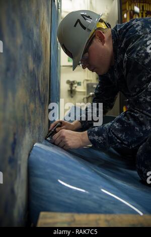 BREMERTON, Washington (Feb. 13, 2017) Mate 1. Klasse David's Aviation Machinist Coulombe, von Palmer, Massachusetts, Schablonen eine Schnittlinie auf Bodenbeläge das Jet Bucht vor Schäden zu schützen und Stolperfallen an Bord der USS John C Stennis (CVN 74). John C Stennis ist derzeit in Vorbereitung auf die geplante schrittweise Verfügbarkeit. Stockfoto