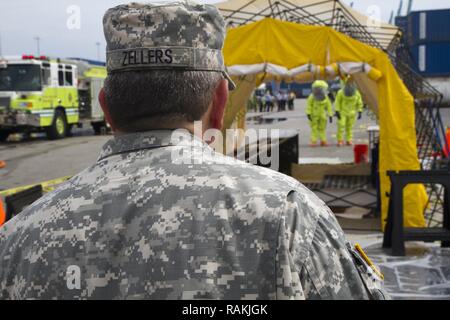 Armee finden Warrant Officer Candidate Tod Zellers gibt Ausbilder zu Soldaten nähert sich der Dekontamination Station am Hafen von Miami bei einer gemeinsamen Gefahr material Übung mit dem Miami-Dade Fire Rescue Department (MDFR) am 13.02.18, 2017 in Miami, Fla. Zellers ist eine zivile Feuerwehrmann mit Seminole County Florida und ist auf 329. der Armee finden Chemische, biologische, radiologische und nukleare (CBRN) Unternehmen (Aufklärung und Überwachung) zugeordnet. Die 329 CBRN-Unternehmens, von Orlando, Fla., 469Th der Armee finden im Krankenwagen, von Wichita, Kan. und Florida Stockfoto