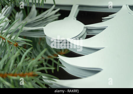 Vorbereitung umweltfreundliche Weihnachtsschmuck Konzept. Nahaufnahme der Stapel weißes Papier, Ornament und Zweig der Grünen Nadelholz Kiefer Stockfoto