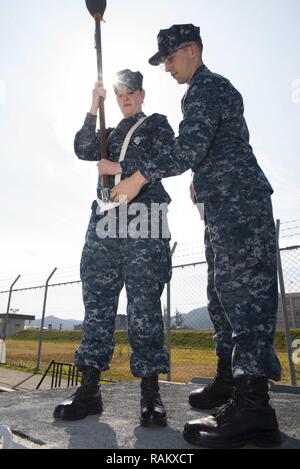 SASEBO, Japan (Feb. 16, 2017) Operations Specialist 2. Klasse Brendan Seehaver, rechts, von Canby, Erz. und Operations Specialist 2. Klasse Karlee Carter, von Redding, Kalifornien, Praxis paradieren die Farben auf der Pier vor Amphibisches Schiff USS BONHOMME RICHARD (LHD6) während einer Räumungsübung Probe für eine bevorstehende Änderung der Befehl Zeremonie. Bonhomme Richard, Vorwärts- und Sasebo, Japan bereitgestellt, das eine schnelle Reaktionsfähigkeit im Falle eines regionalen Kontingenz oder Naturkatastrophe zur Verfügung zu stellen. Stockfoto