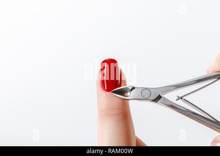 Maniküre mit Häutchen nipper auf Fingernagel mit rotem Nagellack isoliert auf weißem Stockfoto