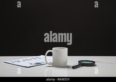 Nahaufnahme der Schale, Lupe und Reisen Zeitung auf Oberfläche in Weiß auf Schwarz Stockfoto
