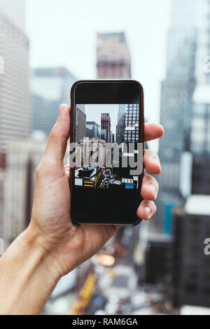7/8 shot fo Mann mit Smartphone unter Bild von New York City Stockfoto