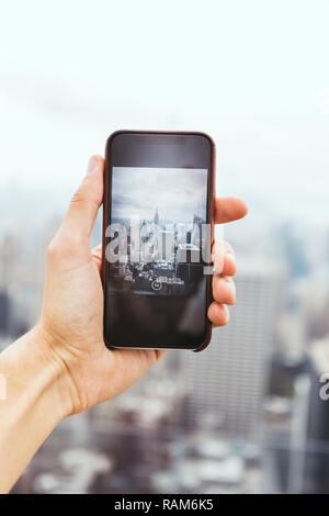 7/8 shot fo Mann mit Smartphone unter Bild von New York City Stockfoto