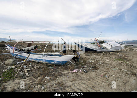 Palu, Indonesien. 04 Jan, 2019. Die Bewohner nehmen den Rest des Holzes in der ehemaligen Lage der tsunami Hauptgewicht auf talise Strand, Palu Bay, Zentral Sulawesi, Indonesien, Freitag (01/02/2019). Erst mehr als drei Monate nach dem Tsunami, die Anzahl der bisher eingeschlossenen Gebiete nicht aufgrund begrenzter Ausrüstung gelöscht. Der Tsunami, der am 28. September 2018 schlug ergab mehr als 2.000 Menschen getötet und mehr als 70.000 Vertriebene. Credit: bmzIMAGES/Alamy leben Nachrichten Stockfoto