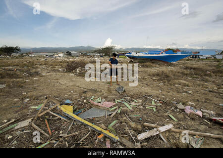 Palu, Indonesien. 04 Jan, 2019. Die Bewohner nehmen den Rest des Holzes in der ehemaligen Lage der tsunami Hauptgewicht auf talise Strand, Palu Bay, Zentral Sulawesi, Indonesien, Freitag (01/02/2019). Erst mehr als drei Monate nach dem Tsunami, die Anzahl der bisher eingeschlossenen Gebiete nicht aufgrund begrenzter Ausrüstung gelöscht. Der Tsunami, der am 28. September 2018 schlug ergab mehr als 2.000 Menschen getötet und mehr als 70.000 Vertriebene. Credit: bmzIMAGES/Alamy leben Nachrichten Stockfoto