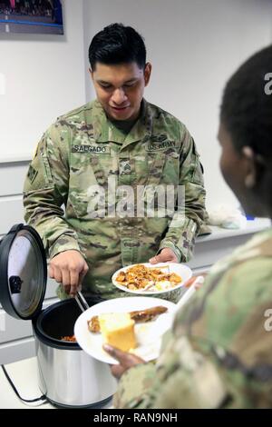 Us-Armee Sgt. Arturo Salgado, 5th Signal Command (Theater) Befehl Fahrer, serviert eine Auswahl an Soul Food nach der US-Armee Garnison Wiesbaden Gemeinschaft Black History Month Einhaltung Feb 15, 2017 Im Tony Bass Auditorium auf Lehm Kaserne. Stockfoto