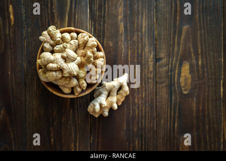 Schüssel mit Ingwer Wurzeln auf dunklem Hintergrund Stockfoto