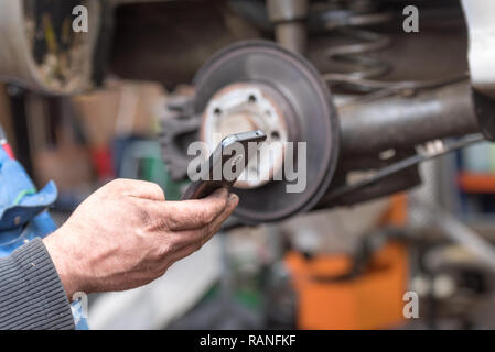 Schmutzige Hände sind Arbeitnehmer mit einem Smart Phone und Eingabe einer Telefonnummer. Stockfoto