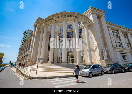 DURRES, Albanien - 17. MAI 2017: Frau auf dem Gehweg, Zebrastreifen vor der albanischen College von Durres. Atemberaubende Architektur mit hohen c Stockfoto