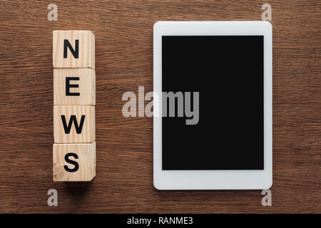 Blick von oben auf die Tablette mit leerer Bildschirm und Holzwürfel mit Word Nachrichten auf hölzernen Tisch Stockfoto