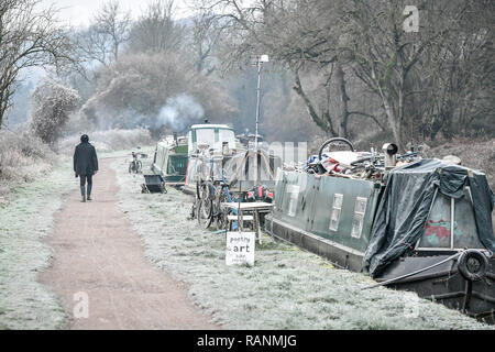 Ein Mann der Vergangenheit frosty narrowboats auf dem Kennet und Avon, Badewanne, da Temperaturen über Teile von Großbritannien unter dem Gefrierpunkt über Nacht gefallen. Stockfoto