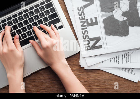 Zugeschnittenes Bild des Journalisten am Laptop an den hölzernen Tisch Stockfoto