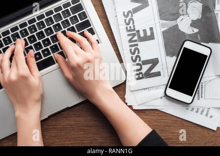 Zugeschnittenes Bild des Journalisten am Laptop an den hölzernen Tisch Stockfoto