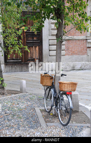 Rund um Italien - ein Einkaufszentrum Fahrrad gegen einen Baum gelehnt in Mailand. Stockfoto