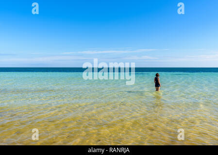 Junge attraktive Frau in Shorts auf dem Meer an einem tropischen Strand. Schöne türkisblaue Wasser des Ozeans. Bahia Honda State Park, Florida Keys Stockfoto