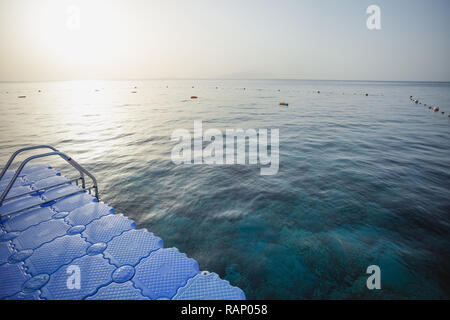 Schönen ruhigen blauen Meer Wasser und Kunststoff Ponton mit Leiter ins Wasser führt. Horizontale Farbfotografie. Stockfoto