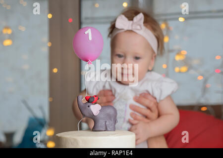 Das Konzept der Kinder Urlaub. Süßwaren Werbung Hintergrund. Mutter ein Jahr alten baby girl Holding. Ersten Geburtstag feiern. Stockfoto