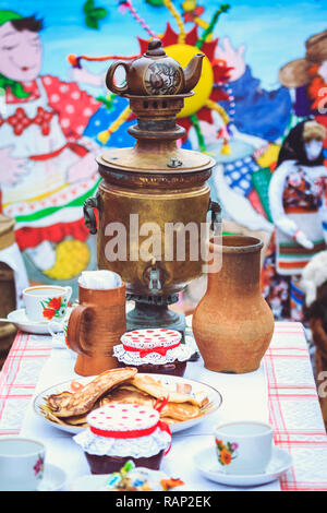 Alte Kupfer Samowar auf dem Tisch mit Speisen und Pfannkuchen Stockfoto