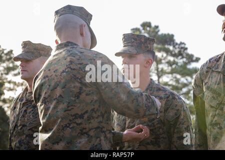 Us Marine Corps Generalmajor John K. Liebe, Kommandierender General, 2nd Marine Division (2d MARDIV), Auszeichnungen Navy und Marine Corps Leistung Medaille Gold Star statt der zweite Auszeichnung der U.S. Navy Petty Officer 2nd class Domenic A. Nasoota, Hospital corpsman, 2d MARDIV, während einer Morgendlichen Farben Zeremonie am Camp Lejeune, N.C., Jan. 22, 2017. Liebe anerkannt Marinesoldaten und Matrosen, innerhalb der 2D-MARDIV, die sich von ihren Kollegen eingestellt, der im vorhergehenden Vierteljahr durch Demonstration ihrer Führungsfähigkeiten, espirit de Corps und deren Fähigkeit und Willen. Stockfoto