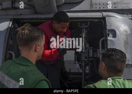 SOUTH CHINA SEA (Feb. 20, 2017) Aviation Ordnanceman 1. Klasse Nicholas Gravesande, aus Brooklyn, New York, lehrt Segler über die M240 Gewehr zu einem MH-60R Sea Hawk Hubschrauber angebracht, um Hubschrauber Maritime Strike Squadron (HSM) 78 angeschlossen, nachdem es auf dem Flugdeck der Arleigh Burke gelandet - Klasse geführte Anti-raketen-Zerstörer USS Wayne E.Meyer (DDG108) für eine Auffüllung vorzubereiten-auf-See mit Henry J. Kaiser-Klasse unterwegs Auffüllung öler USNS Tippecanoe (T-AO 199). Wayne E.Meyer ist in regelmäßigen Western Pacific Bereitstellung mit der Carl Vinson Carrier Strike Group als Teil o Stockfoto