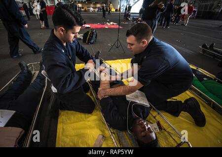 Pazifik (Feb. 22, 2017) Segler Praxis schweren Trauma erste Hilfe Techniken während einer Messe Unfallversicherung Bohrer in den Hangar Bucht der Flugzeugträger USS Theodore Roosevelt (CVN 71). Theodore Roosevelt ist derzeit vor der Küste von Südkalifornien die Durchführung von routinemäßigen Ausbildungsmaßnahmen. Stockfoto