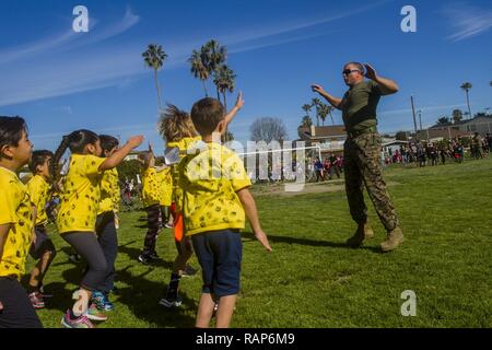 Oberstleutnant Lukas McConnell, der Executive Officer für 5 Marines Regiment, 1st Marine Division, führt die Studenten in einem dynamischen Warmup während der jährlichen Jog-a-thon von Las Palmas Grundschule in San Clemente, Kalifornien, 24.02.2017. Marines besuchte ihre Unterstützung auf dem Weg zu ihrer Gemeinschaft zu zeigen und motivieren die Schülerinnen und Schüler die Veranstaltung zu genießen und Spaß zu haben. Stockfoto