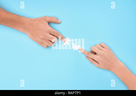 7/8 Schuß von Mann und Frau mit weißen Puzzleteile auf blauem Hintergrund, Zusammenarbeit Konzept Stockfoto