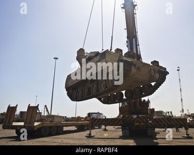 Ein M2/M3 Bradley Fighting Fahrzeug per Kran auf einen Tieflader auf die usns Mendonca an Shuaiba Port, Kuwait, am 28.02.2017, transportiert. Die mendonca Dient zum Importieren und US-Militär Fahrzeuge zur Unterstützung von Maßnahmen in der USCENTCOM AOR exportieren. Stockfoto