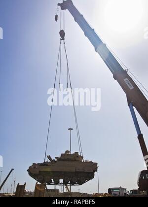 Ein M2/M3 Bradley Fighting Fahrzeug per Kran auf einen Tieflader auf die usns Mendonca an Shuaiba Port, Kuwait, am 28.02.2017, transportiert. Die mendonca Dient zum Importieren und US-Militär Fahrzeuge zur Unterstützung von Maßnahmen in der USCENTCOM AOR exportieren. Stockfoto