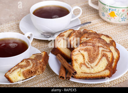 In Scheiben geschnitten Zimt swirl Brot auf eine Platte mit zwei Tassen Kaffee und Zucker Schale Stockfoto