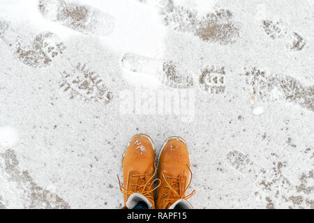 Blick von oben auf die gelbe Schuhe / Stiefel stehen auf dem Eis in der Nähe des Meeres. Winter Saison. Stockfoto
