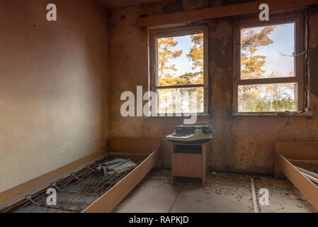 Prerow, Deutschland - 30. Dezember 2018: Eine alte Schreibmaschine steht in einem verlassenen Schlafzimmer. Der Putz bröckelt von den Wänden. Das Zimmer gehört zu einer Stockfoto