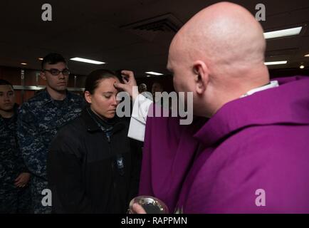 YOKOSUKA, Japan (Mar. 1, 2017) Lt. j.g. Jason Burchell, eine Marine Kaplan, von Arlington, Virginia, verwendet Palm Asche das Zeichen des Kreuzes auf die Stirn des Feuers Controlman 3. Klasse Chelsea Ahfarnfeketa zu markieren, von der Stony Brook, New York, zu USS Blue Ridge LCC (19), in der Kapelle des Schiffes an Bord der Marine nur vorwärts zugeordnet - bereitgestellt Flugzeugträger USS Ronald Reagan (CVN 76). Aschermittwoch ist der erste Tag der Fastenzeit, 46 Tage vor Ostern. Ronald Reagan, das Flaggschiff der Carrier Strike Group 5, bietet eine Bekämpfung bereit, Kraft, schützt und verteidigt die kollektive maritime Interessen seiner Stockfoto