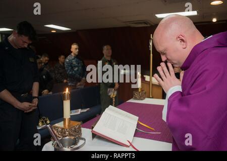 YOKOSUKA, Japan (Mar. 1, 2017) Lt. j.g. Jason Burchell, ein Navy chaplain zugeordnet zu den Flugzeugträger USS Ronald Reagan (CVN 76) führt, Matrosen in einem Gebet während einer römisch-katholischen Gottesdienst in der Kapelle. Ronald Reagan, das Flaggschiff der Carrier Strike Group 5, bietet eine Bekämpfung bereit, Kraft, schützt und verteidigt die kollektive maritime Interessen seiner Verbündeten und Partnern in der Indo-Asia-Pazifik-Region. Stockfoto