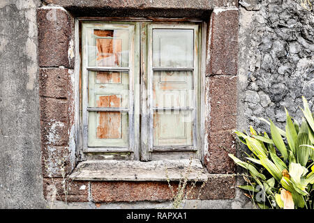 Eine marode Holzfenster in einem alten Haus aus Stein auf Madeira, Portugal. Das Fenster von innen durch die Fensterläden geschlossen ist, werden die Frames sind unlackiert und Stockfoto