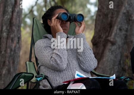 HALEIWA, Hawaii - Armee Ehepartner Juanita Terrell beobachtet den Ozean für Buckelwale im Pua'ena Point Beach Park für die 2017 Sanctuary Ozean zählen Projekt, Feb 25, 2017. Pua'ena Punkt ist einer der Standorte, an denen die freiwilligen Anschluss buckelwal Sichtungen. Das Heiligtum Ozean zählen tritt im Januar, Februar und März eines jeden Jahres und wird durch den hawaiischen Inseln Buckelwal National Marine Sanctuary koordiniert. Gebietsansässige und Gebietsfremde in der Zählung teil als Freiwilliger oder Site Leader. Stockfoto