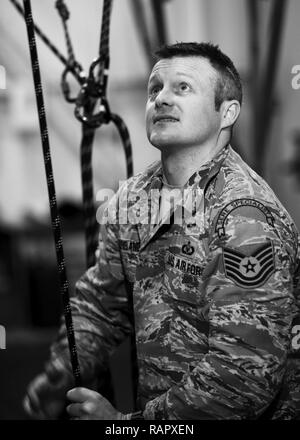 Tech. Sgt. Clifton Cleveland, 5 Operational Support Squadron überleben, Steuerhinterziehung, Widerstand und Flucht Spezialist, wirft das Bodenpersonal in simulierten Fallschirm Kabelbäume über Riemenscheiben am Minot Air Force Base, N.D., Jan. 22, 2017. Abgänge und Rettungsgerät Ausbildung lehrt Personal, wie man ein Flugzeug sicher verlassen und wieder in den Boden nach einem Notfall. Stockfoto