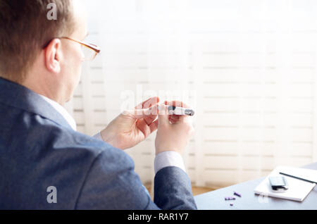 Mittleres Alter Mann Pierce seine Fingerspitze vor Blutprobe mit persönlichen glucometer. Für text Stockfoto